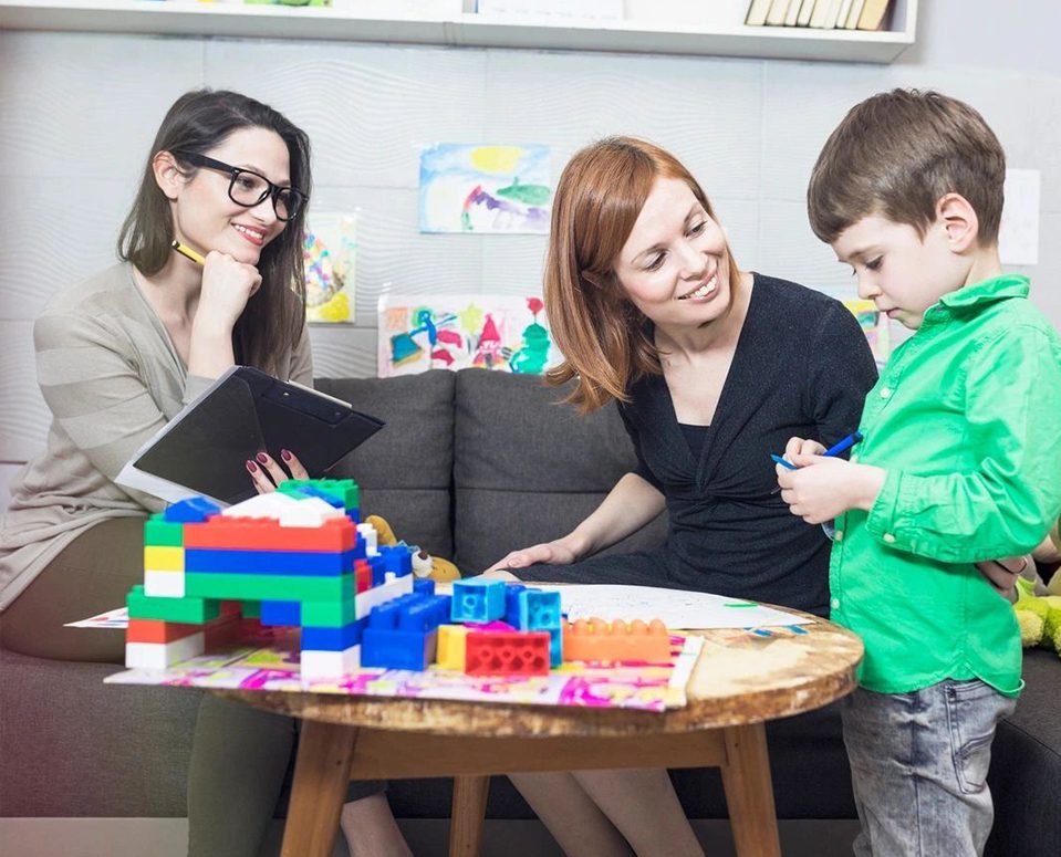 A woman and two children playing with blocks.